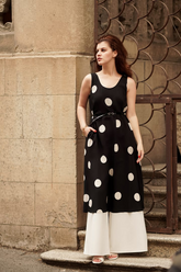 a lady in a black dress with white polka dots and a pair of white wide leg pants